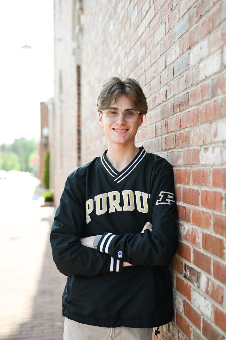 Joey in a Purdue jacket with his arms crossed