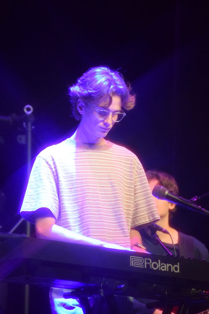 Joey playing a Roland keyboard under purple stage lights